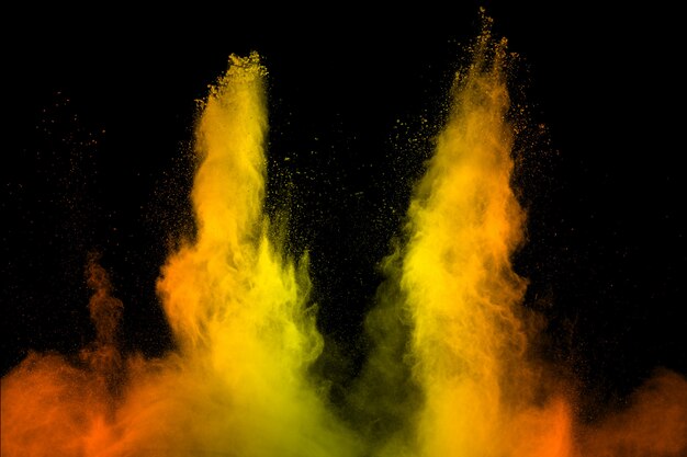 Желтый оранжевый пыль частиц взрыва на черном фоне.