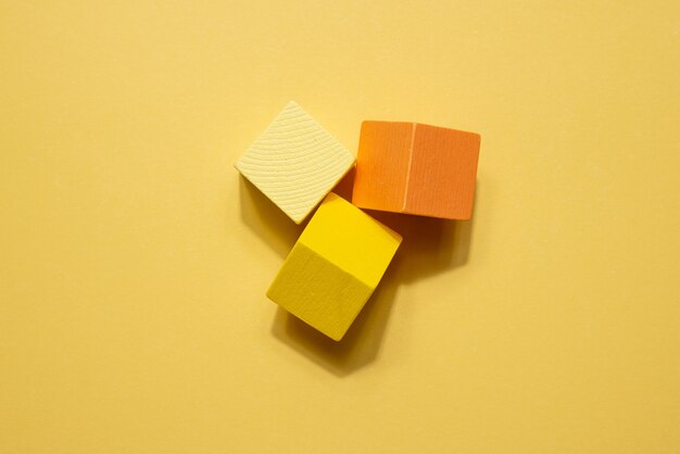 Yellow orange geometrical figures still life composition. Wooden game cube objects on yellow background. simplicity concept top view with shadow top