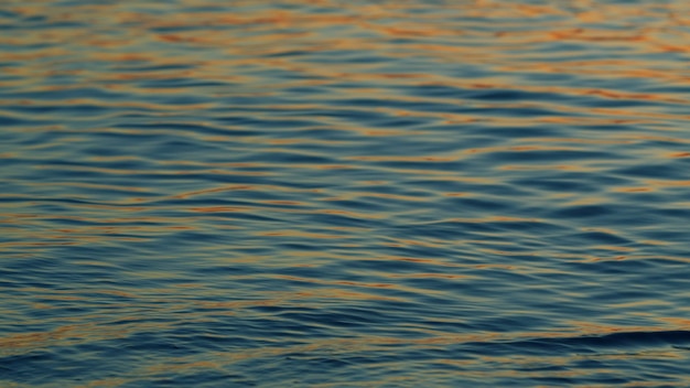 Yellow and orange sea at sunset golden texture water surface small waves sunset reflections on sea