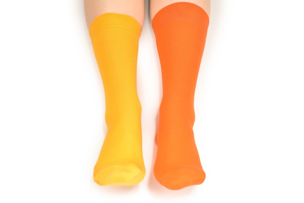 Yellow and orange socks on woman foot isolated on white background.