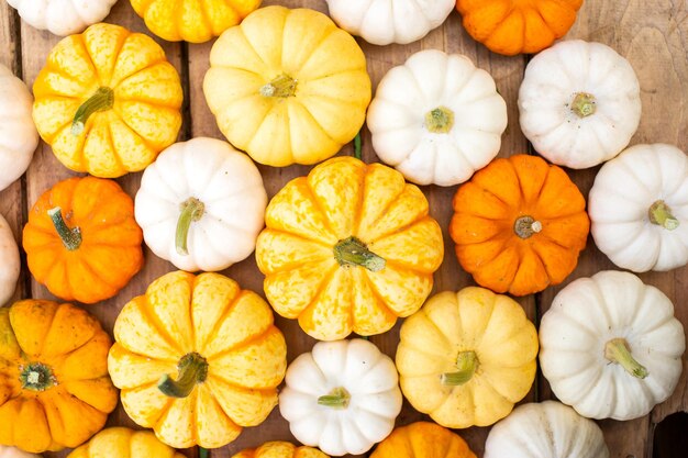 Yellow orange and white pumpkins are lying on a wooden table