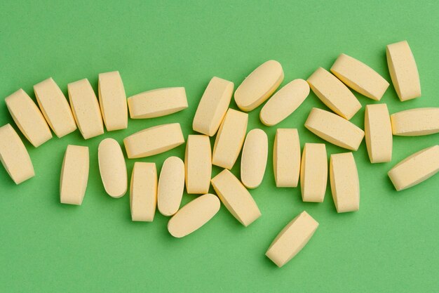 Yellow oval tablets on a green background top view