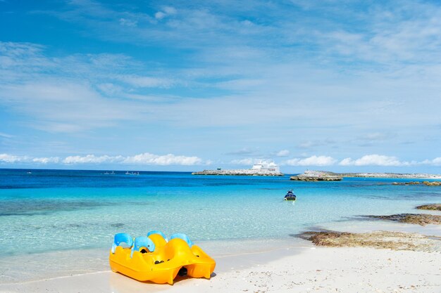 Yellow paddle boat on white sand beach of tropical sea resort on sunny summer day on blue sky