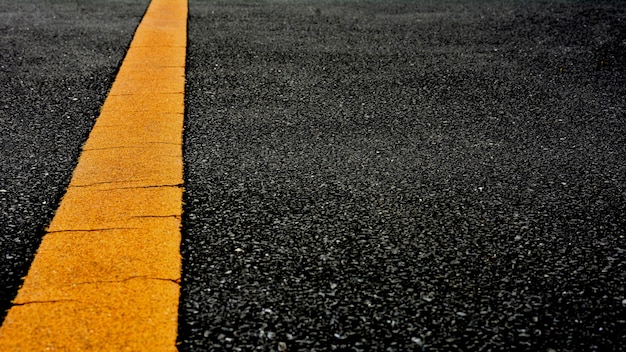 Foto linea di verniciatura gialla su asfalto nero. sfondo del trasporto spaziale