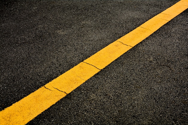 Photo yellow paint line on black asphalt.