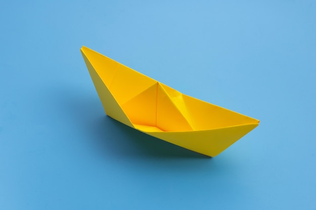 Yellow paper boat on blue surface. Copy space