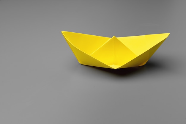 Желтый бумажный кораблик на сером крупным планом