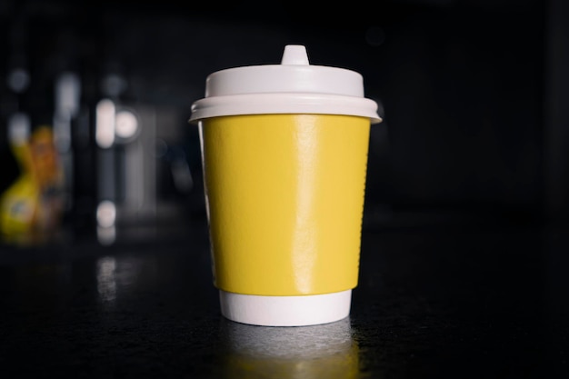 Yellow paper coffee mug on a dark background Empty space for text and design The form for the name of the coffee or company or coffee shop