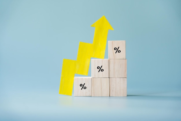 Yellow paper cut arrow going up positive trend on wooden blocks with percentages