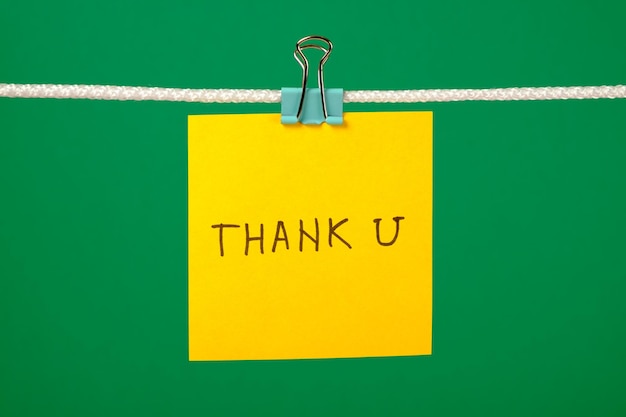 Желтая бумажная записка на веревке с текстом "Спасибо".