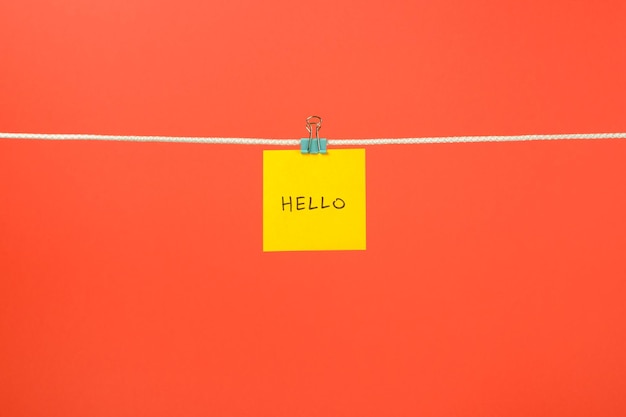 Photo yellow paper sheet on the string with text hello