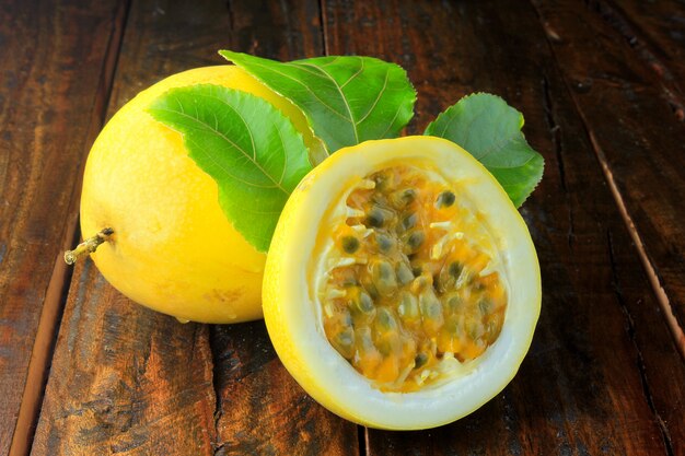 Yellow passion fruit with leaf and passion fruit cut in half on wooden table. 