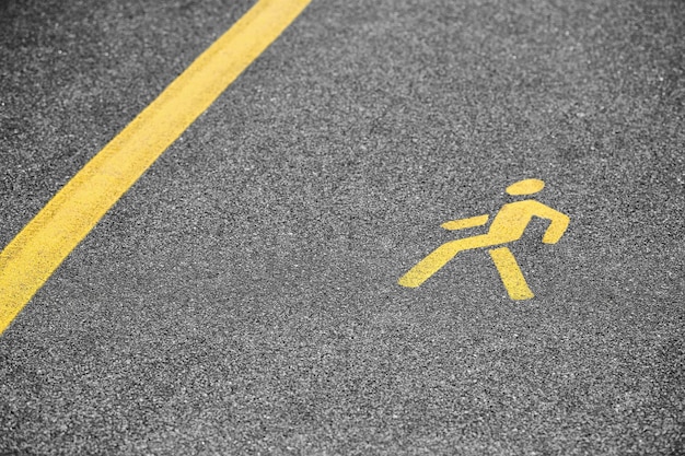 Yellow pedestrian sign on sidewalk, safe road traffic near
highway. pedestrian road sign on asphalt track, yellow marking for
road traffic safety, selective focus