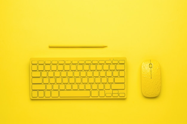 Yellow pencil, yellow keyboard and yellow mouse on a yellow background. monochrome image. flat lay