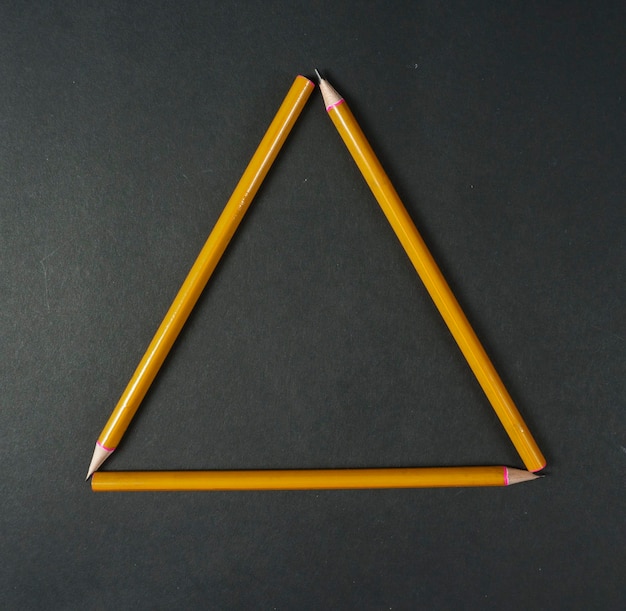 Photo yellow pencils triangle on black backgroundback to school backgroundtop view