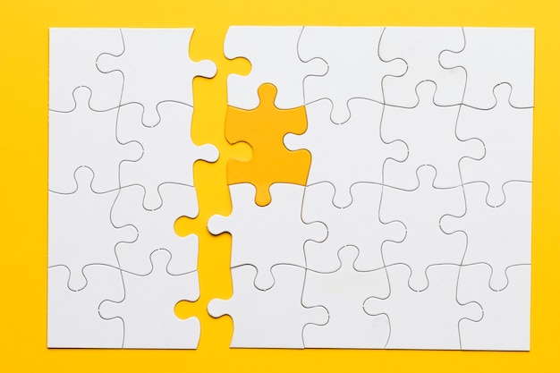 Photo yellow piece connect with white puzzle pieces on plain background