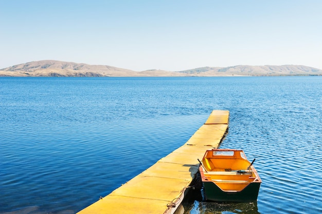 Yellow pier and boat on the lake. Autumn landscape