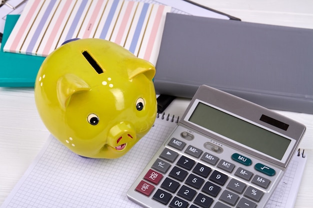 Yellow piggy bank with calculator and copy books.