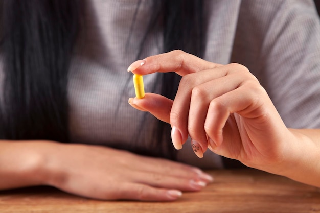 yellow pill in woman hand