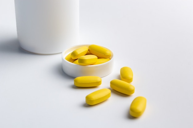 黄色い錠剤と白い背景で隔離のボトル