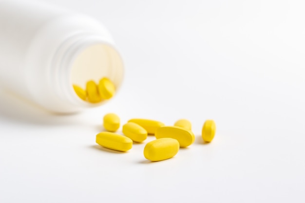 yellow pills and bottle isolated on white background