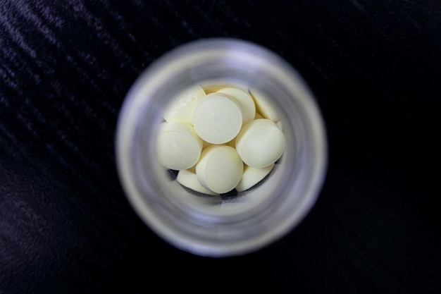 Yellow pills in glass jar on table