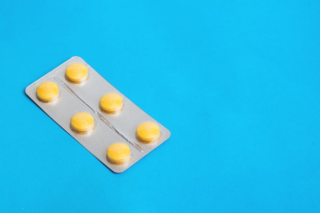 Yellow pills in pack on blue background