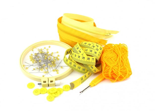 Spilla gialla, bottone, filato, cerniera e strumenti per cucire