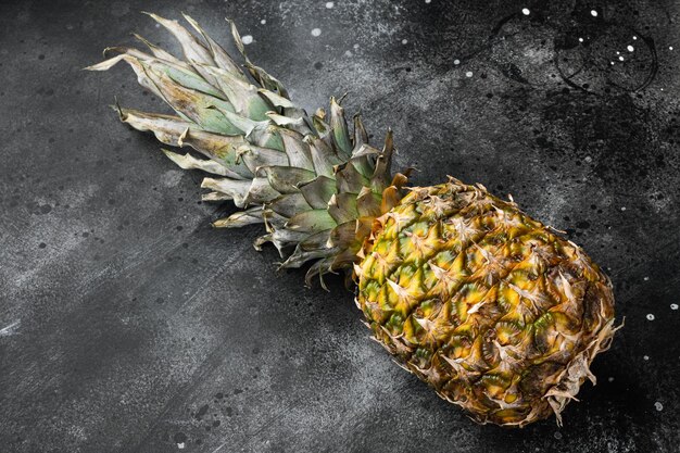 Yellow Pineapple or ananas on black dark stone table background with copy space for text