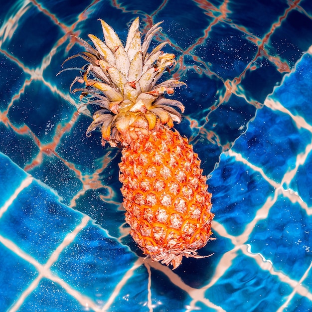 Yellow pineapple floating in a pool. Minimal