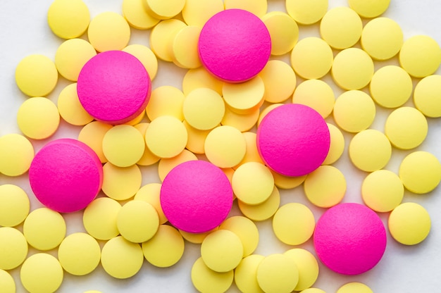 Foto pillole gialle e rosa su bianco