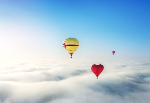 Yellow, pink and red ballons over the clouds