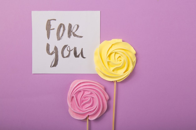 Желтые и розовые розы конфеты в пастельных тонах на деревянной палочке с карточкой «для тебя» на цветном фоне, Валентина, День матери.