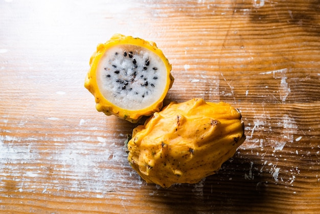 Желтый тропический фрукт питахайя, драконий фрукт, разрезанный пополам на деревянной доске