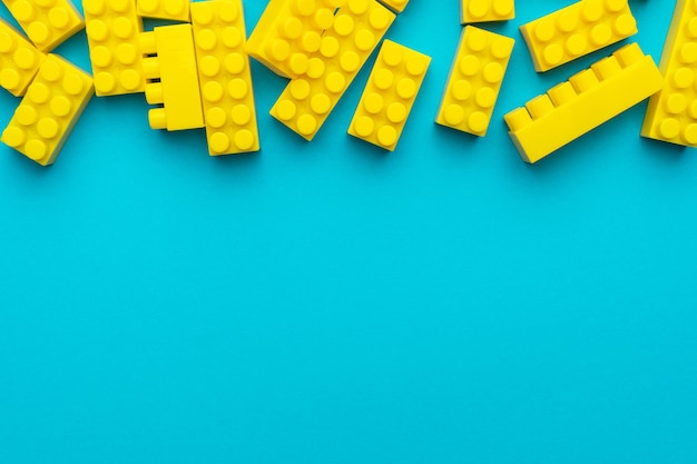 Photo yellow plastic building blocks on turquoise blue background with copy space