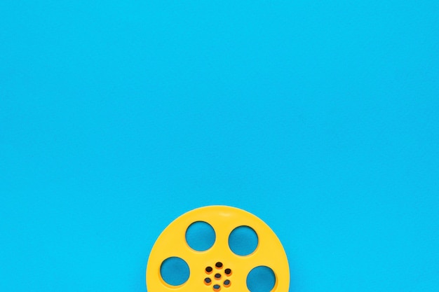 Yellow plastic film reel on a blue background The minimal concept of cinema Flat lay