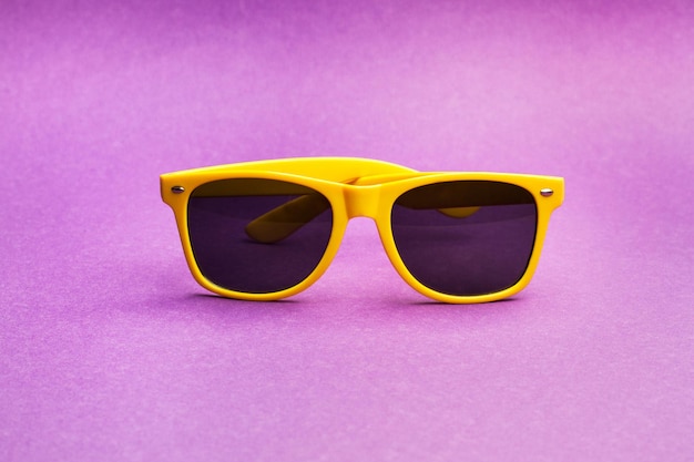 Yellow plastic frame sunglasses on a purple background