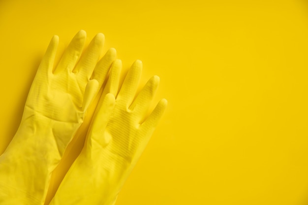 Yellow plastic gloves on yellow wall