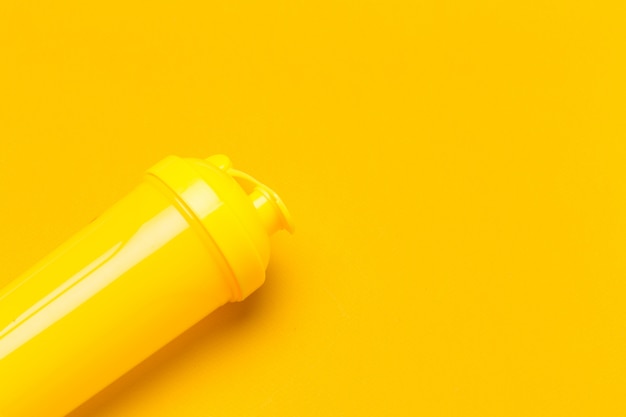 Желтый пластиковый протеиновый шейкер на ярком фоне