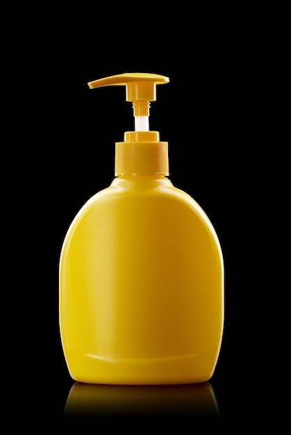 Yellow plastic pump bottle isolated on a black background. hand disinfection dispenser, personal hygiene concept.