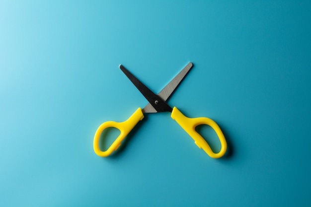 Yellow plastic scissors on blue paper. - background