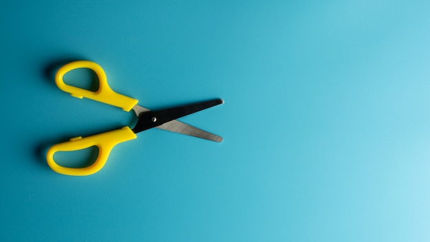 Yellow plastic scissors on blue paper. - background