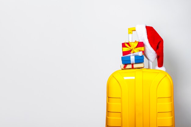Yellow plastic suitcase wearing a red Santa Claus hat