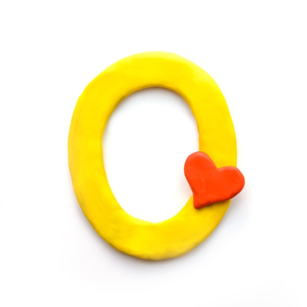 Желтая пластилиновая буква O английского алфавита с красным сердцем, означающая любовь