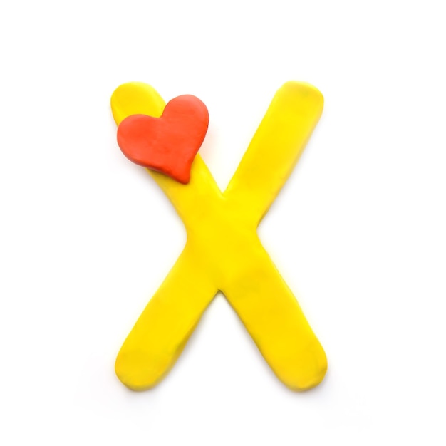 Yellow plasticine letter X English alphabet with red heart meaning love