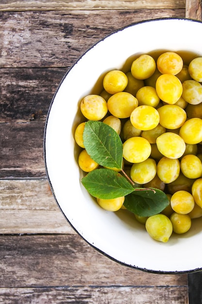 Photo yellow plums. fresh ripe sweet fruits on old wooden boards rough background.