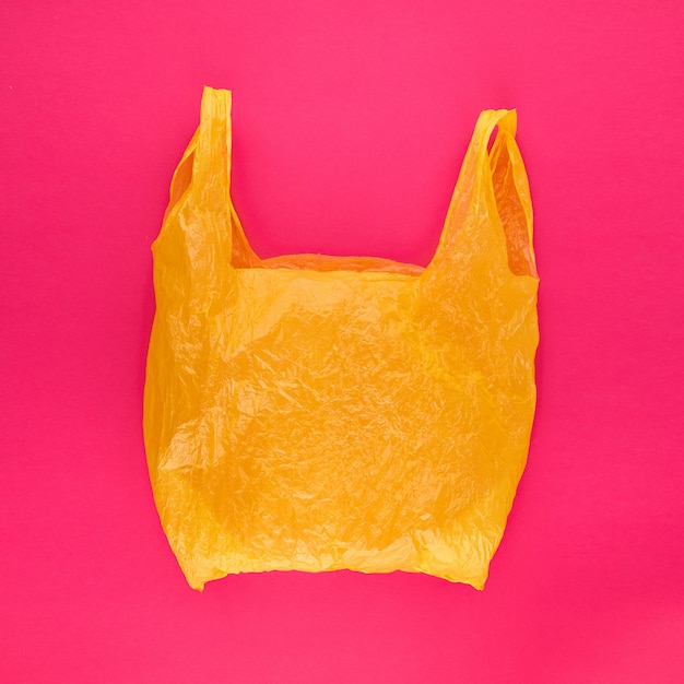 Yellow polyethylene bag on vivid pink abstract background