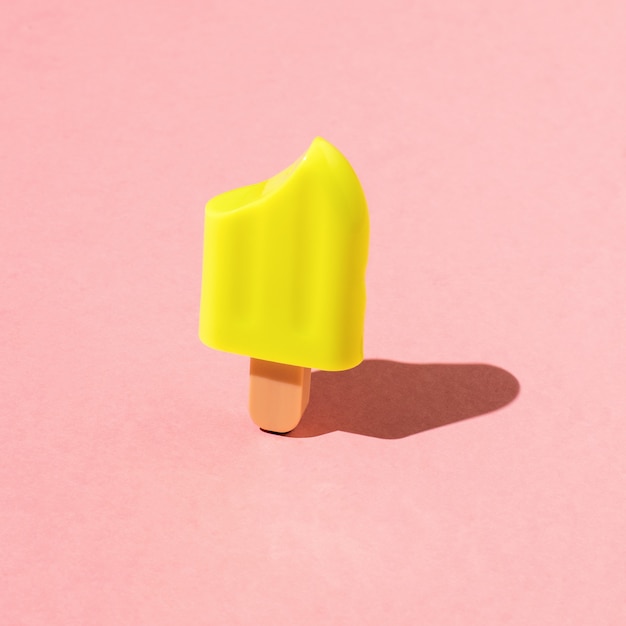 Yellow popsicle made of frozen juice on a red background. A popular summer snack.