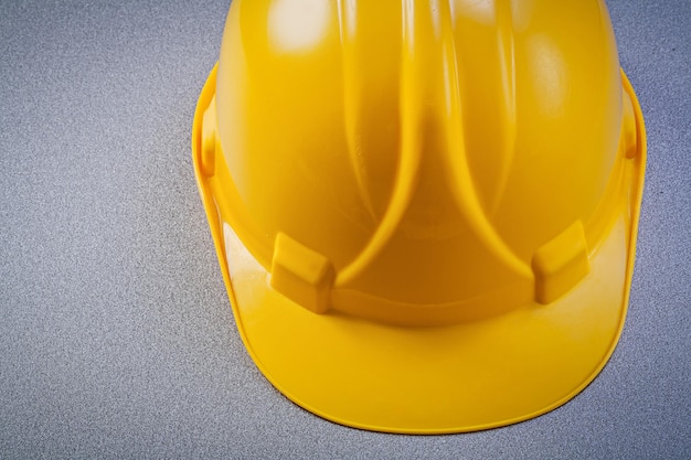 Yellow protective building helmet on grey background top view construction concept.