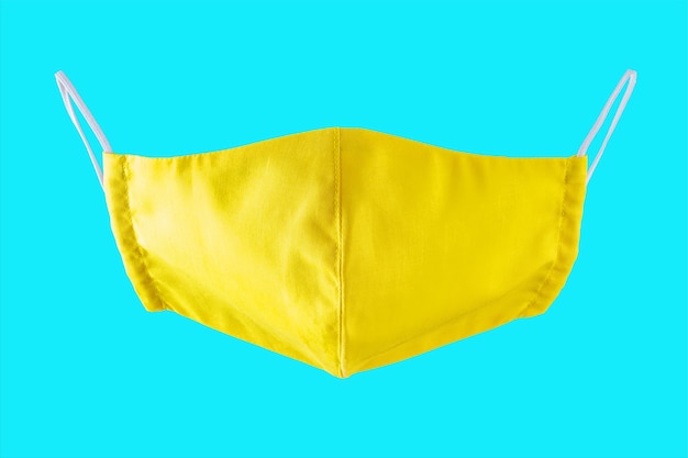 Yellow protective face mask on blue background. Reusable face mask isolated. Face antivirus mask